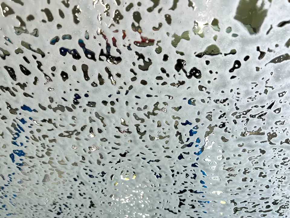 In the car wash. Looking at the windshield from the inside as the soap and suds run down it.